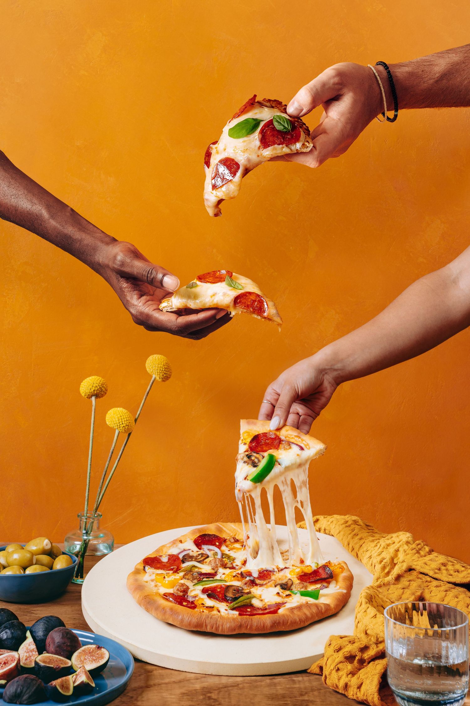 Cheesy pizza slices being pulled apart on white plate against orange background.