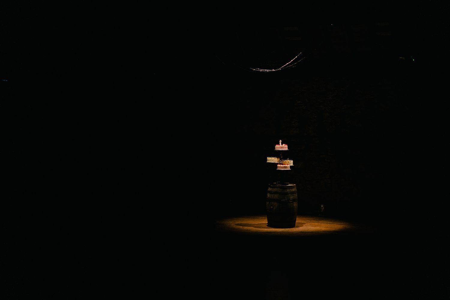 Three tiered wedding cake on an old whiskey barrel with dramatic lighting at Kinkell Byre Wedding Photography
