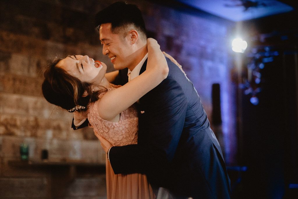 Romantic dance moment in dimly lit venue with blue lighting.