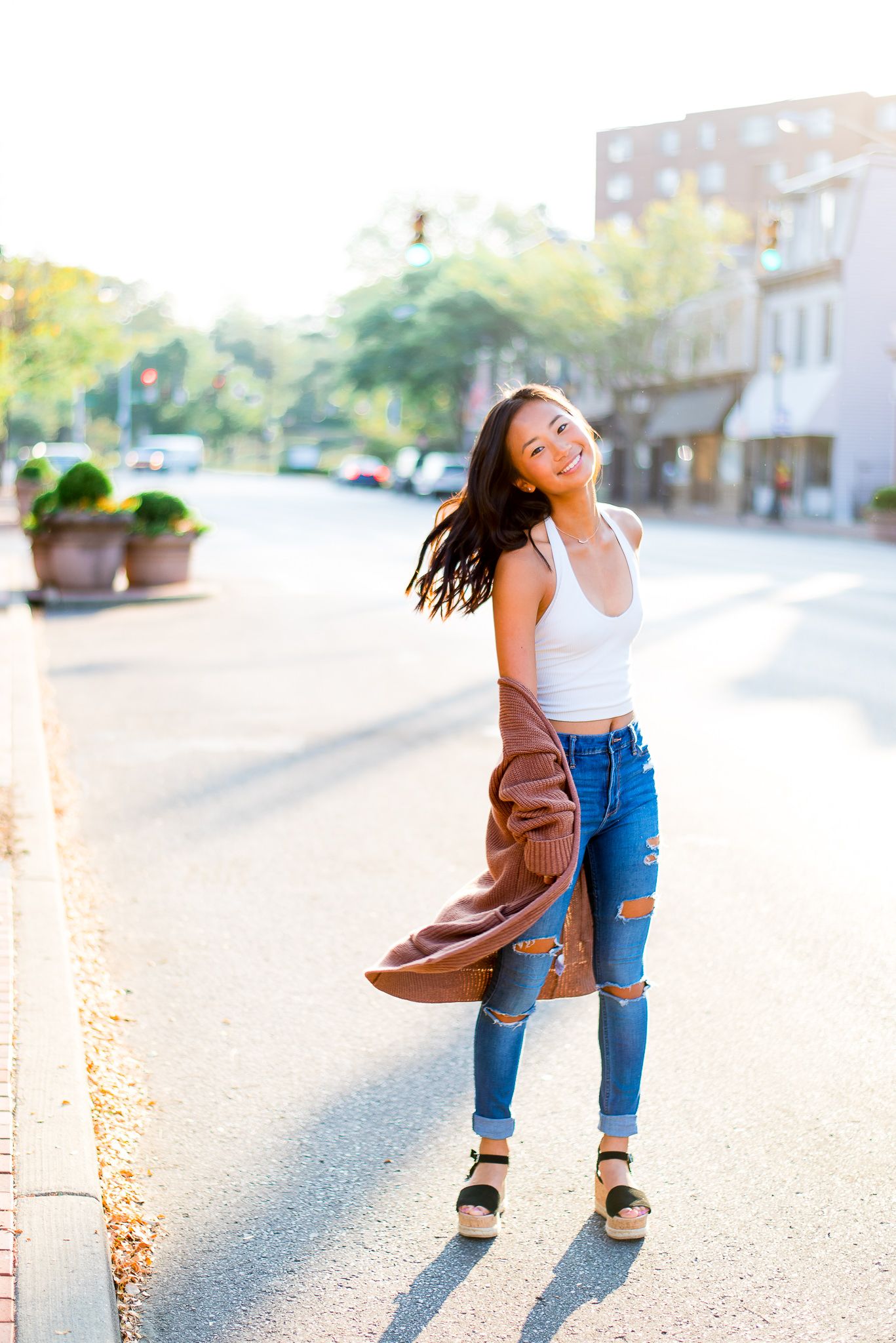 high school senior twirling around in the street at sunrise