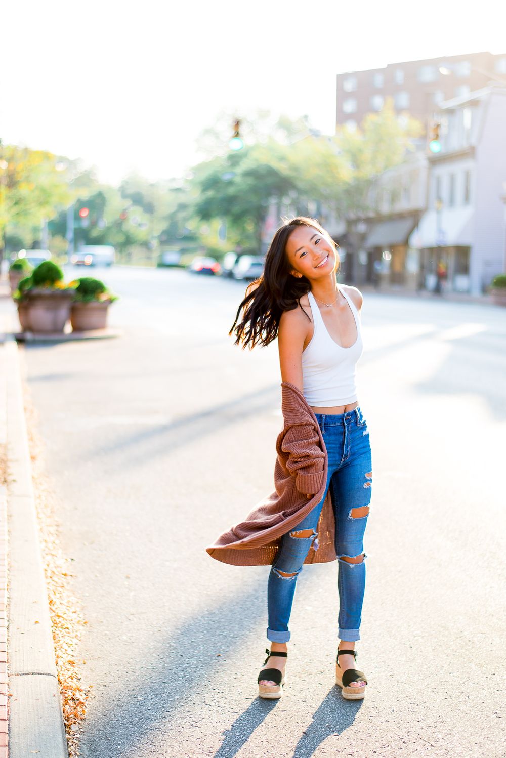 high school senior twirling around in the street at sunrise