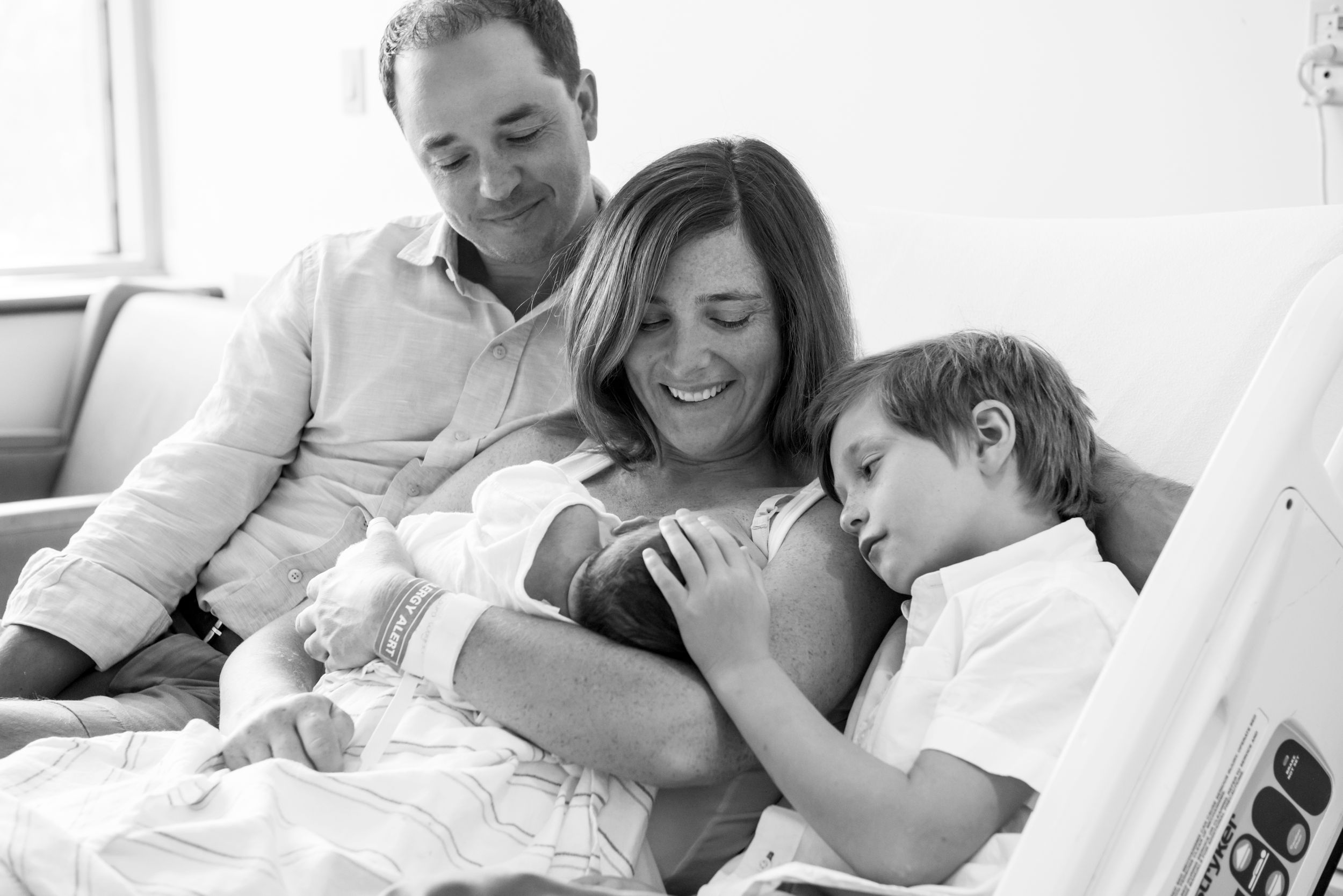 Family gazing at newborn baby during Fresh 48 session by Heidi Harting Photography