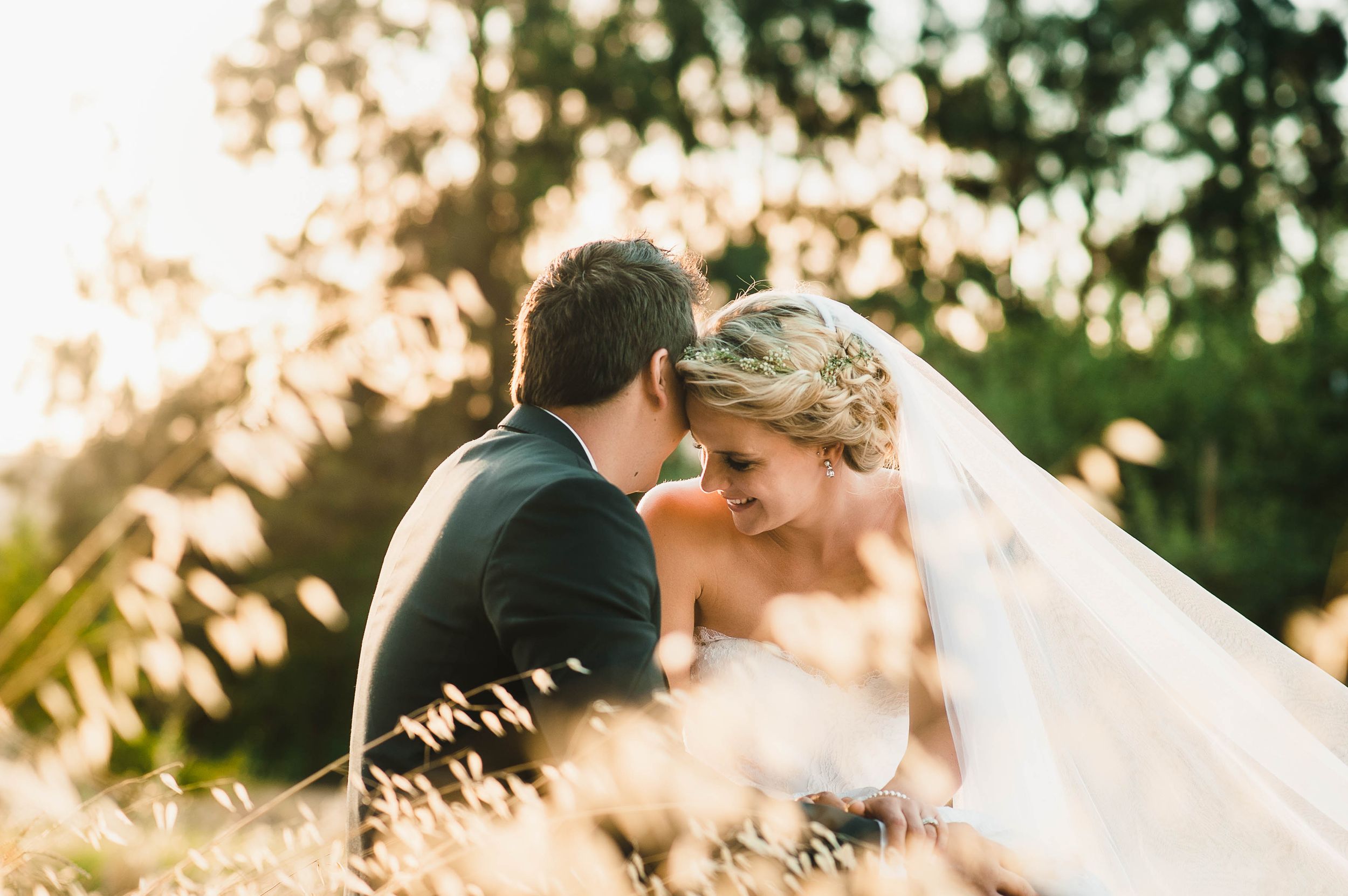 bride and groom in tall grass at sunset