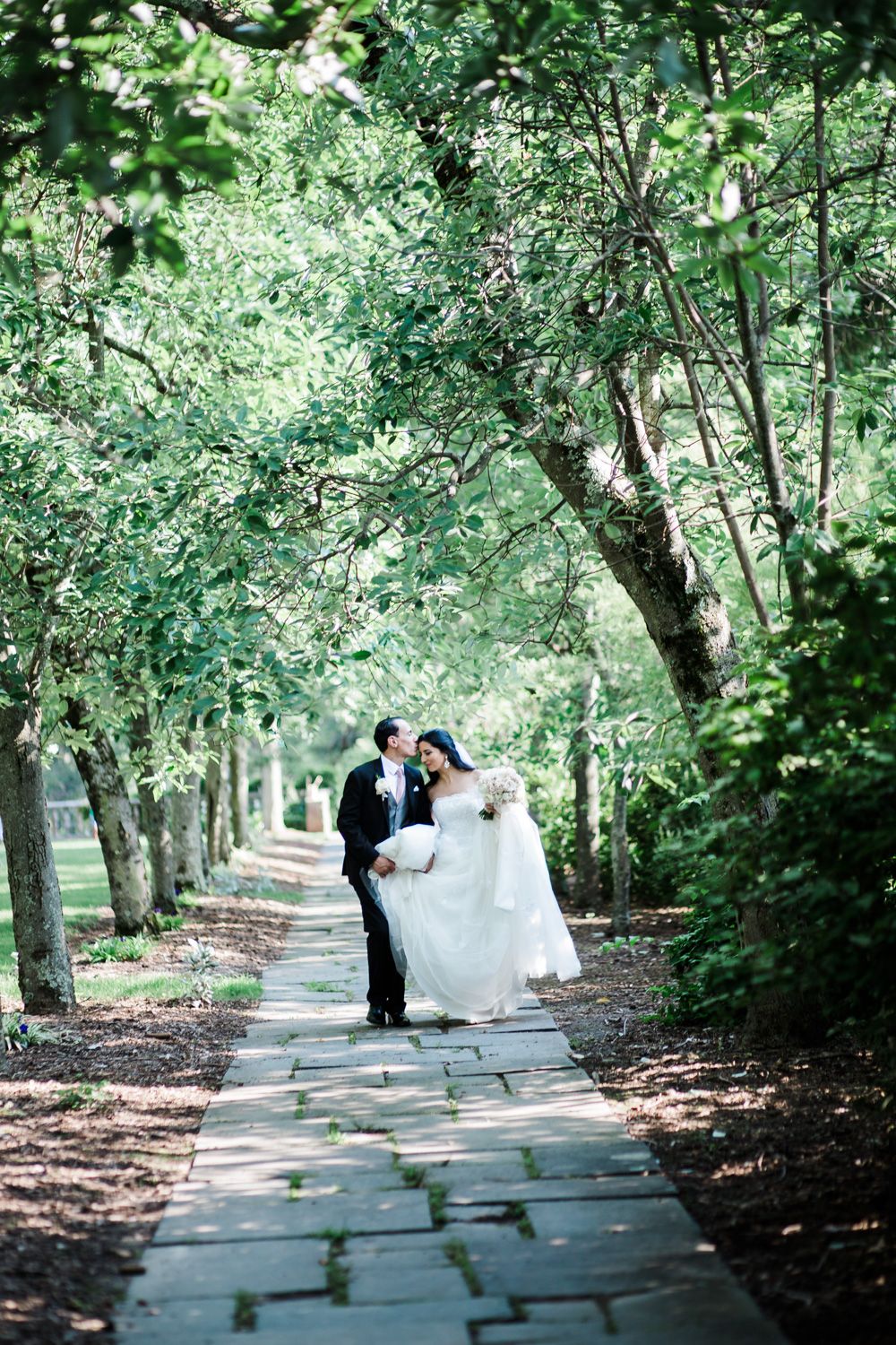 Bride and groom walk down a stone path at the New Jersey Botanical Gardens