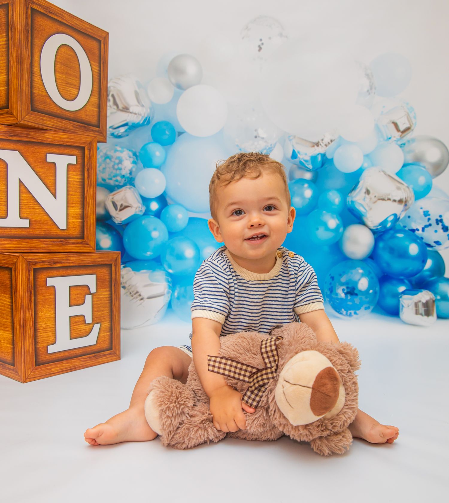 Cake smash photo setup with wooden ONE blocks and blue balloon decorations.