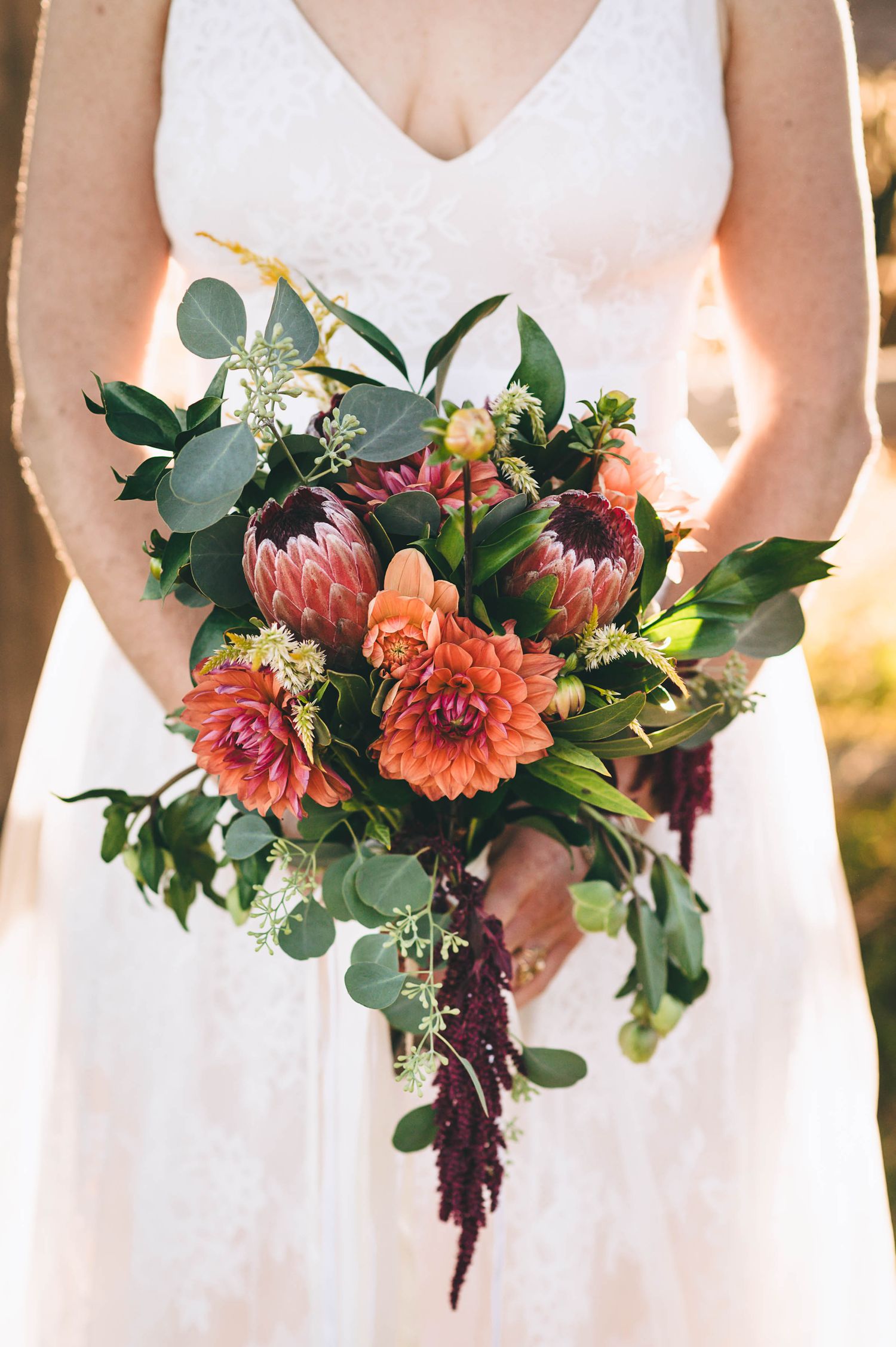 Bridal bouquet of orange, red, and pink flowers.