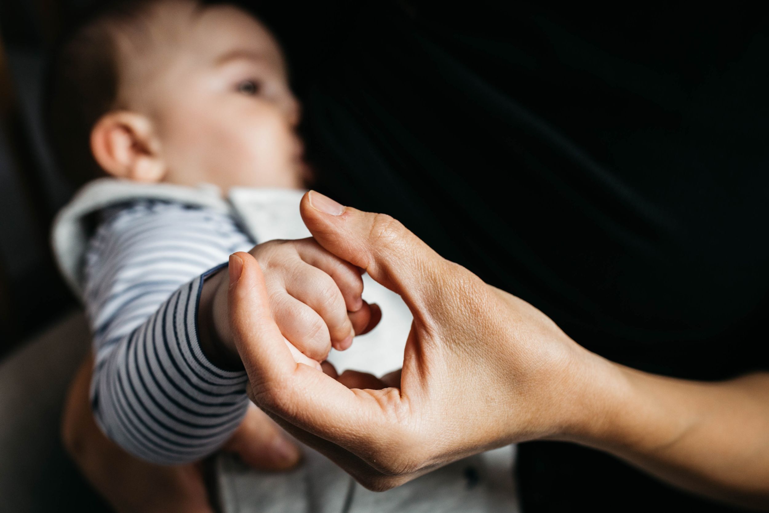 breastfeeding mum holding baby boy hand