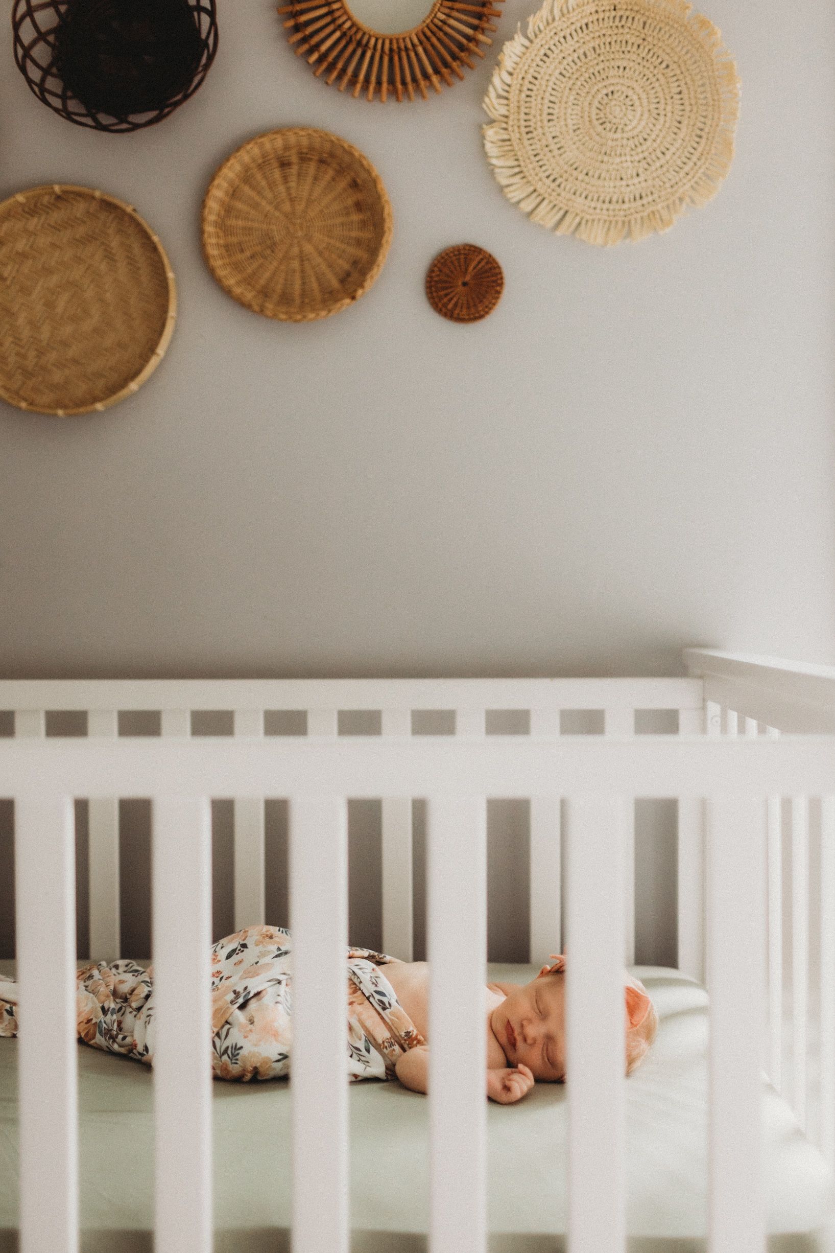 Newborn sleeping in her boho inspired crib, face towards the camera. Photo by newborn photographer, Elizabeth Pachniak.