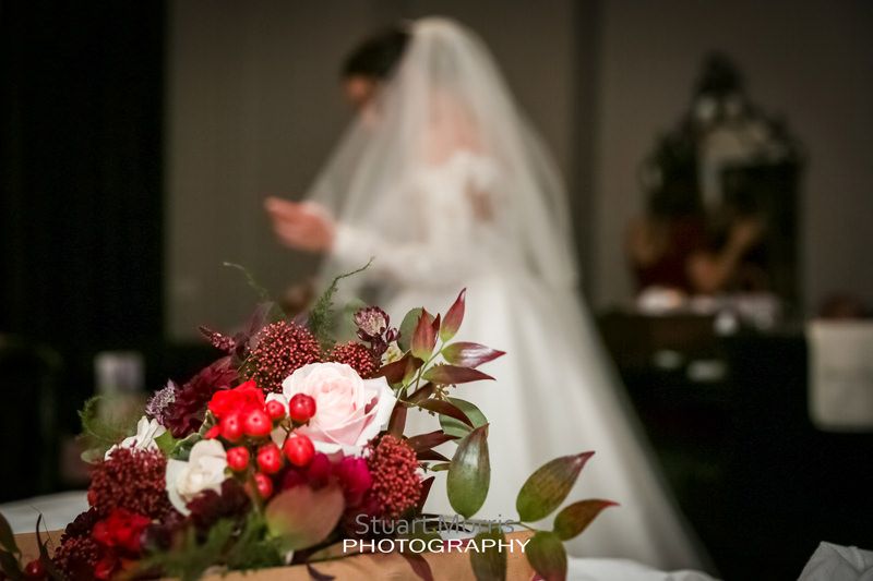 wedding bouquet in the foreground with the bride out of focus in the distance