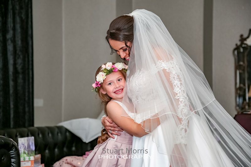bride gets a hug from the young flower girl