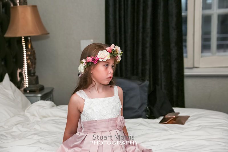 young flower girl sitting on the bed during the bridal prep at 30 james street