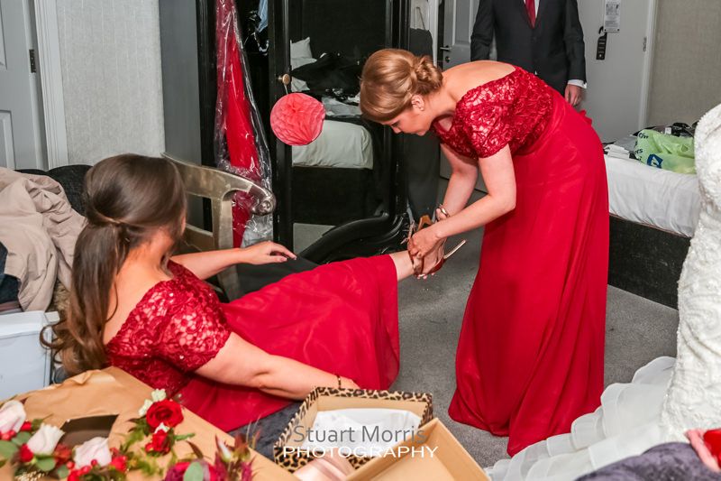 bridesmaid helping another bridesmaid put her shoe on