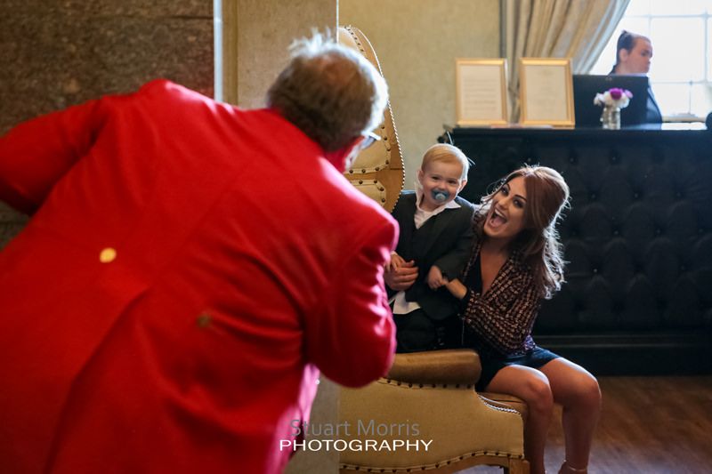 wedding toastmaster plays peekaboo with a young boy sitting on his mums knee at 30 james street