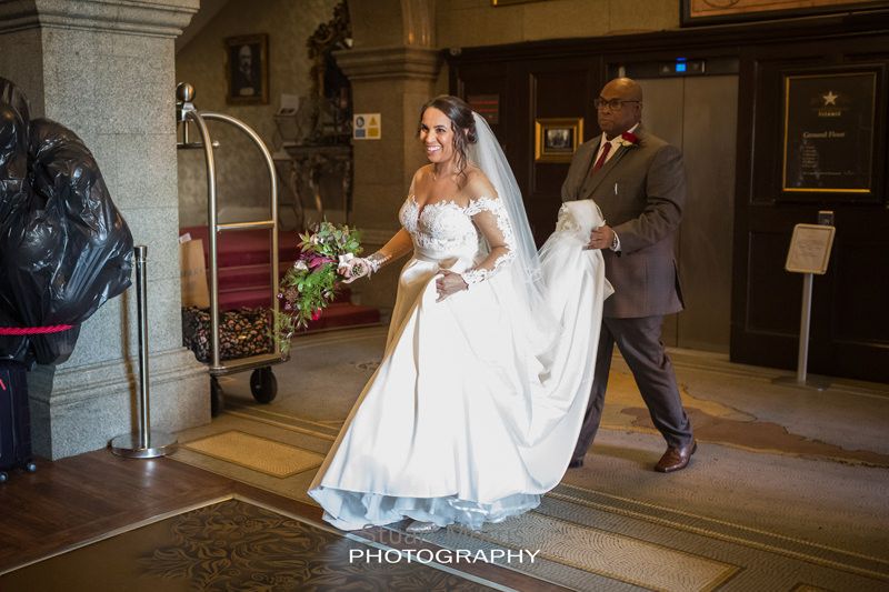 bride walks through the lobby at 30 james street he dad carrying the back of her dress