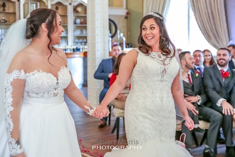 brides turn to look at each other smiling during the ceremony