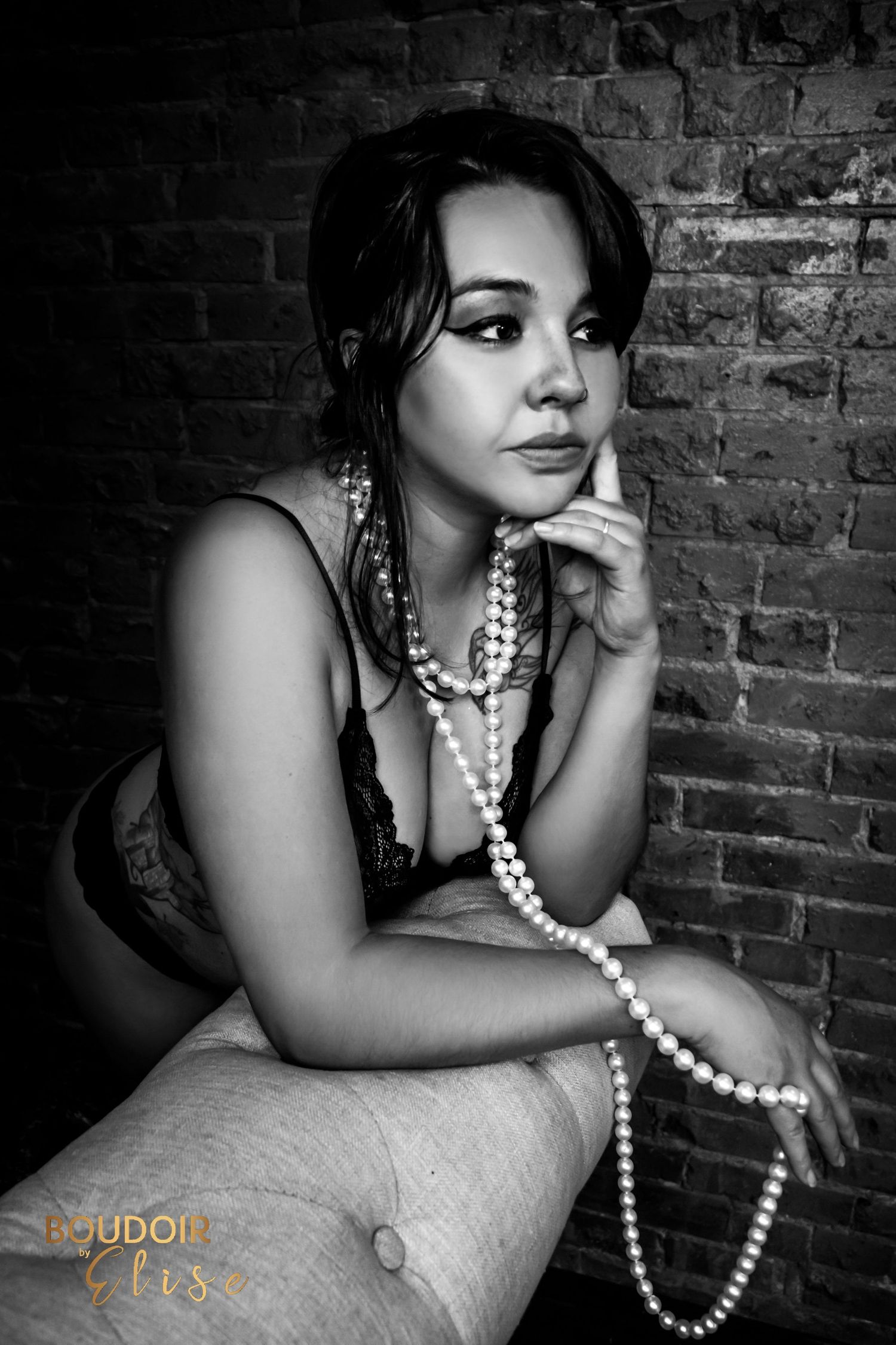 BOUDOIR BY ELISE GORGEOUS WOMAN WEARING PEARLS WHILE LEANING OVER A CHAISE LOUNGE IN BLACK AND WHITE
