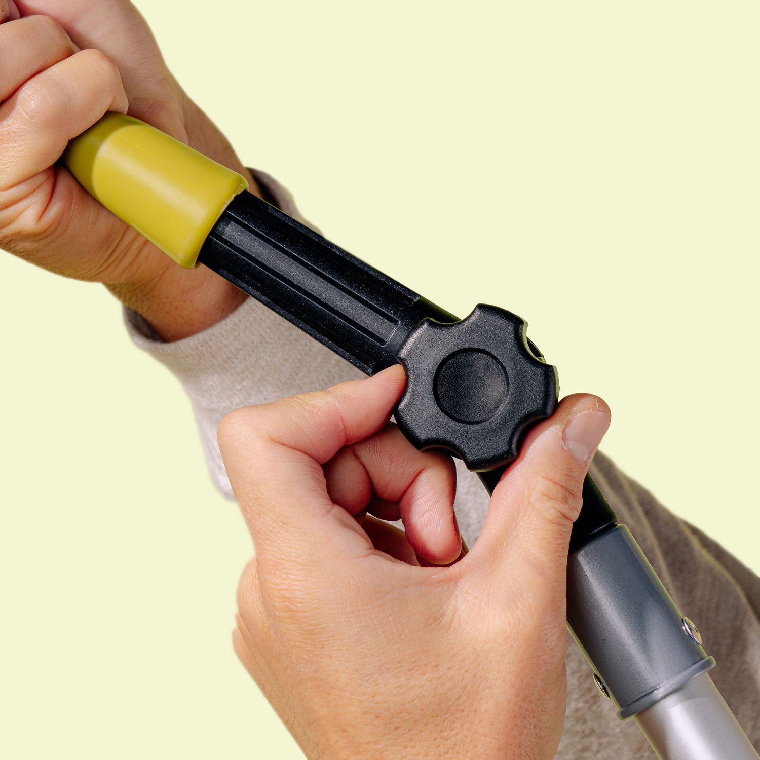 Close-up of hands adjusting the locking mechanism on an extendable cleaning pole.