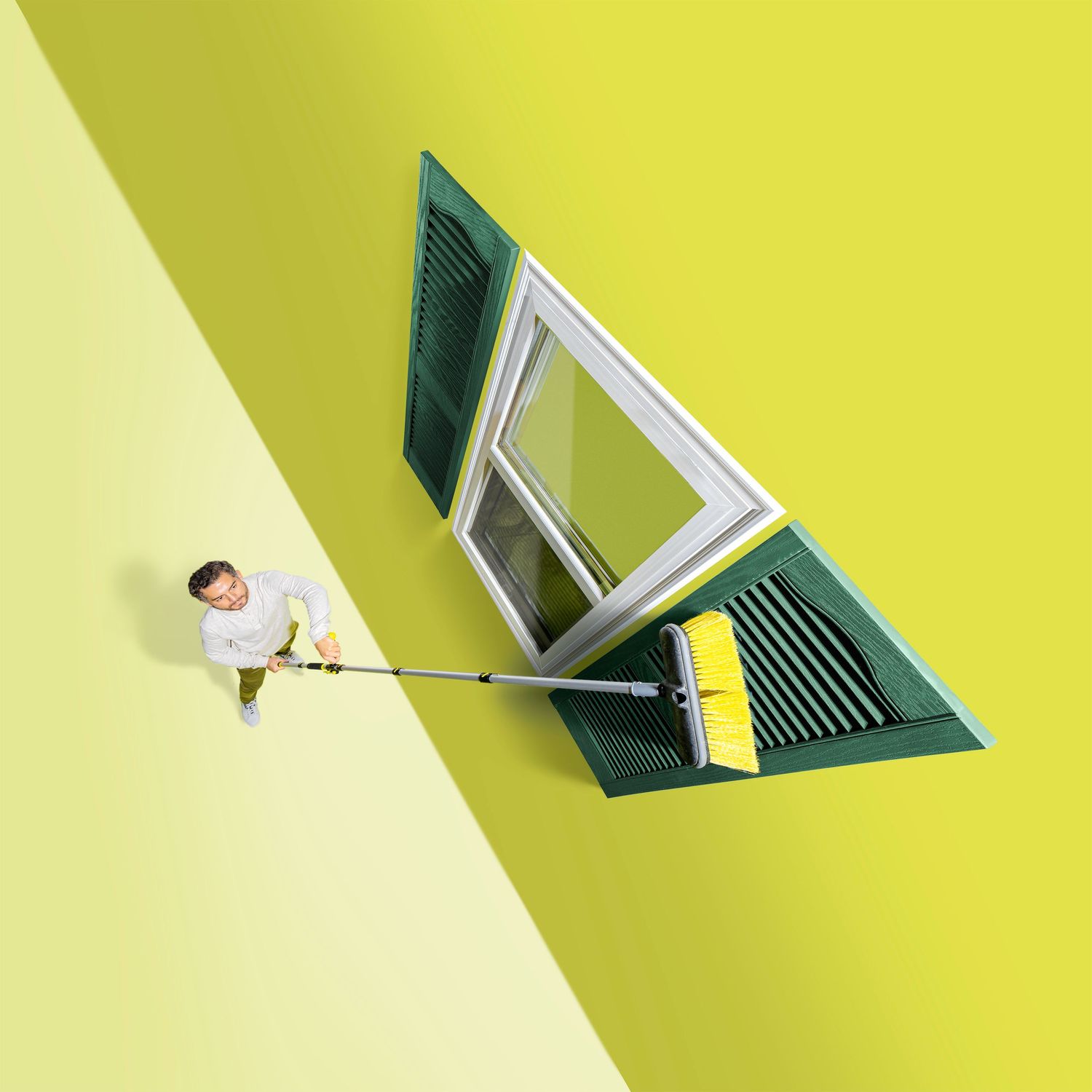 Artistic perspective of window cleaning tool reaching toward green-framed window on yellow wall.