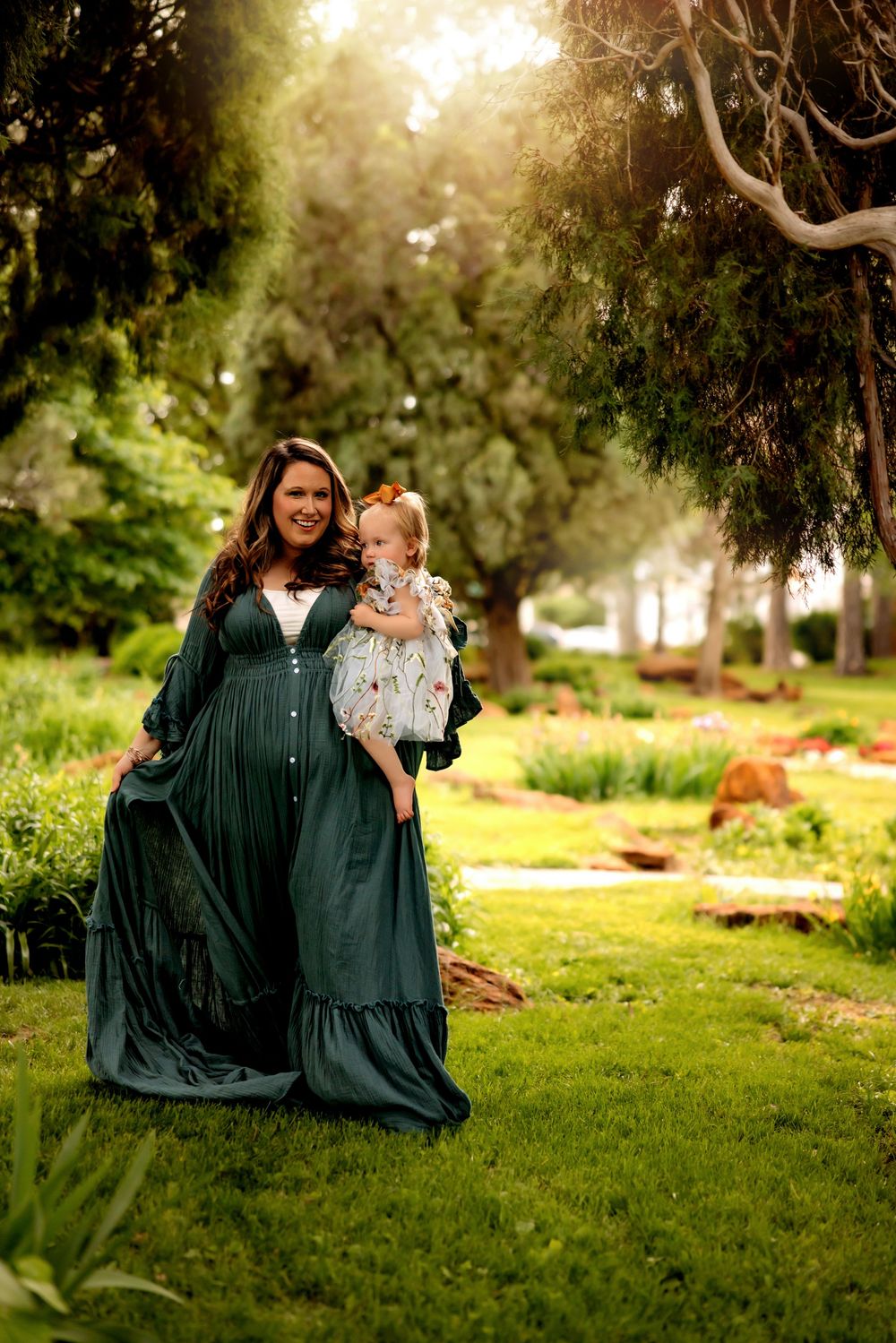 A beautiful garden scene shows flowing green dress against lush foliage as sunlight streams through trees in the background.
