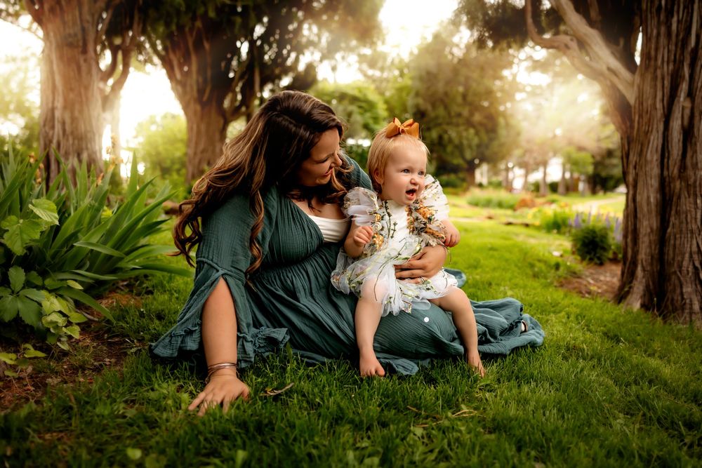 Two people sit together on a blue blanket in a lush garden setting during golden hour lighting.