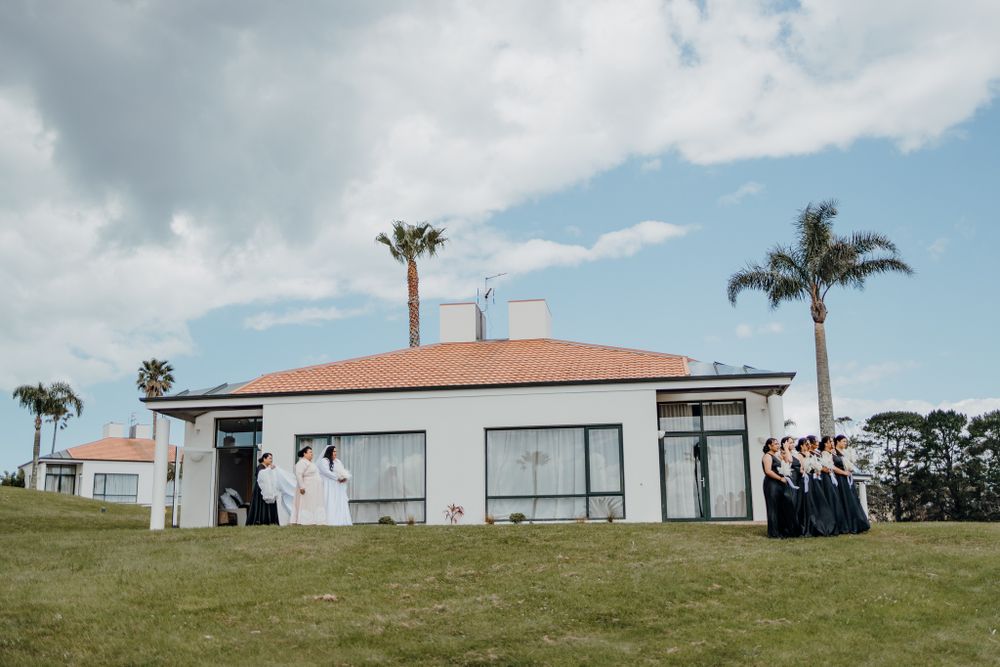 Modern white building with palm trees serves as backdrop for wedding party photos.