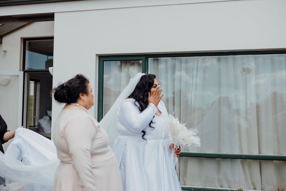 Wedding preparation scene outside modern white building with reflective windows.