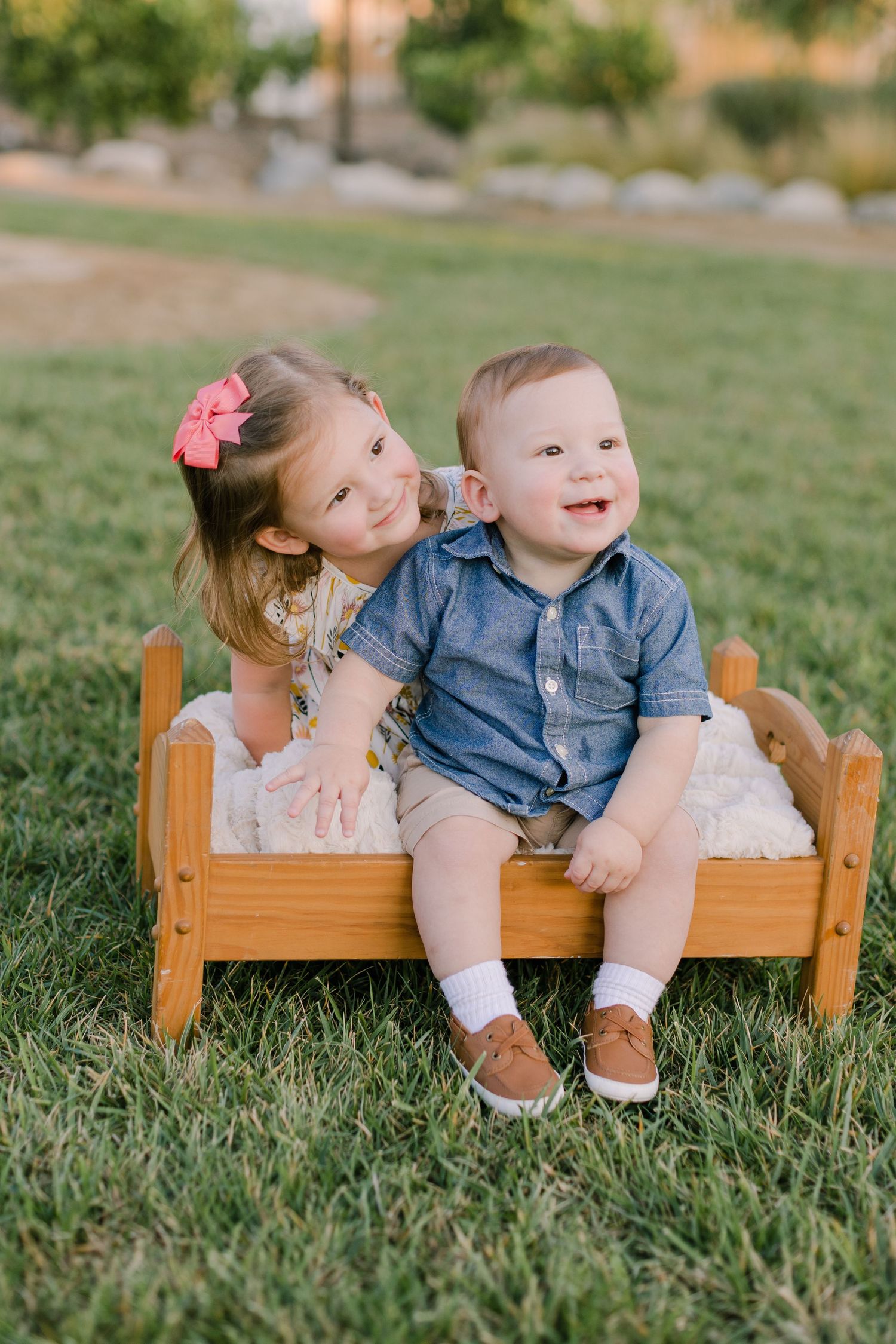 Sibling photo shoot on wood baby bed on grass