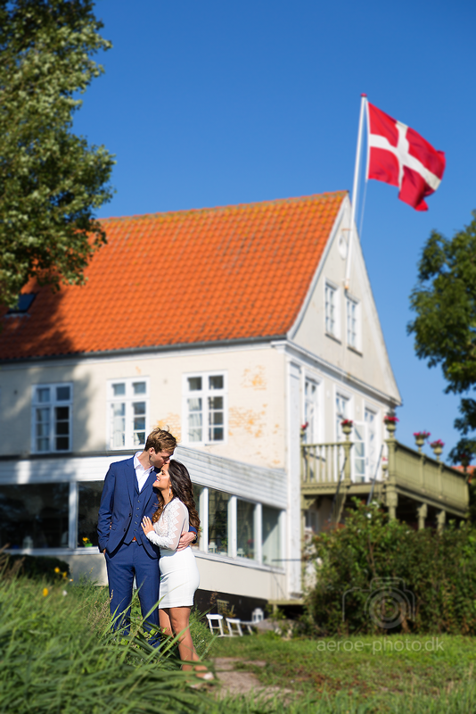 Beautiful and happy couple, nice background, blue sky and the wind is moving the flag in just the right way