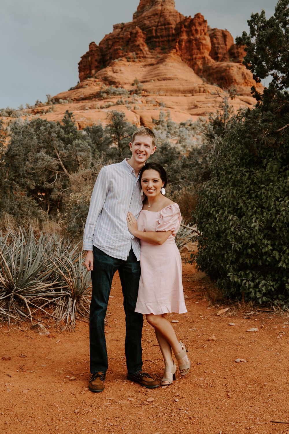 couple smiling with their arms around each other with the Bell Rock in the background