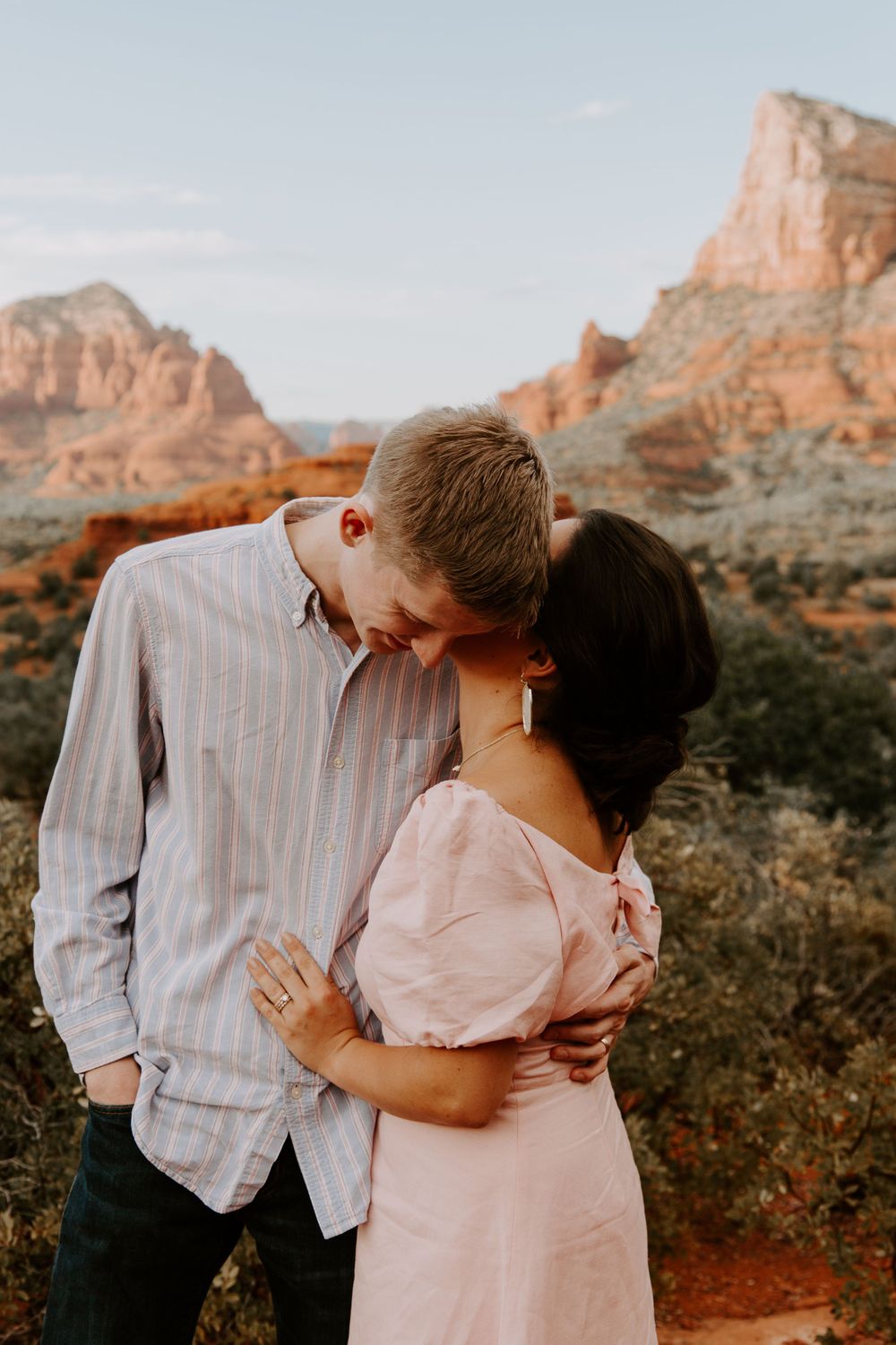 woman whispering into her partners ear during their desert engagement session