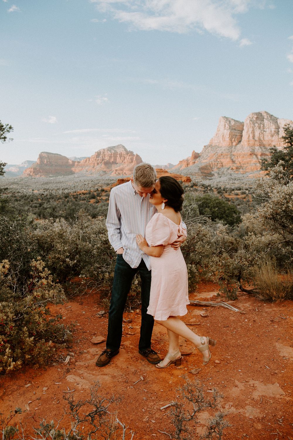 woman whispering into her partners ear as the sun is setting during their Bell Rock engagement session