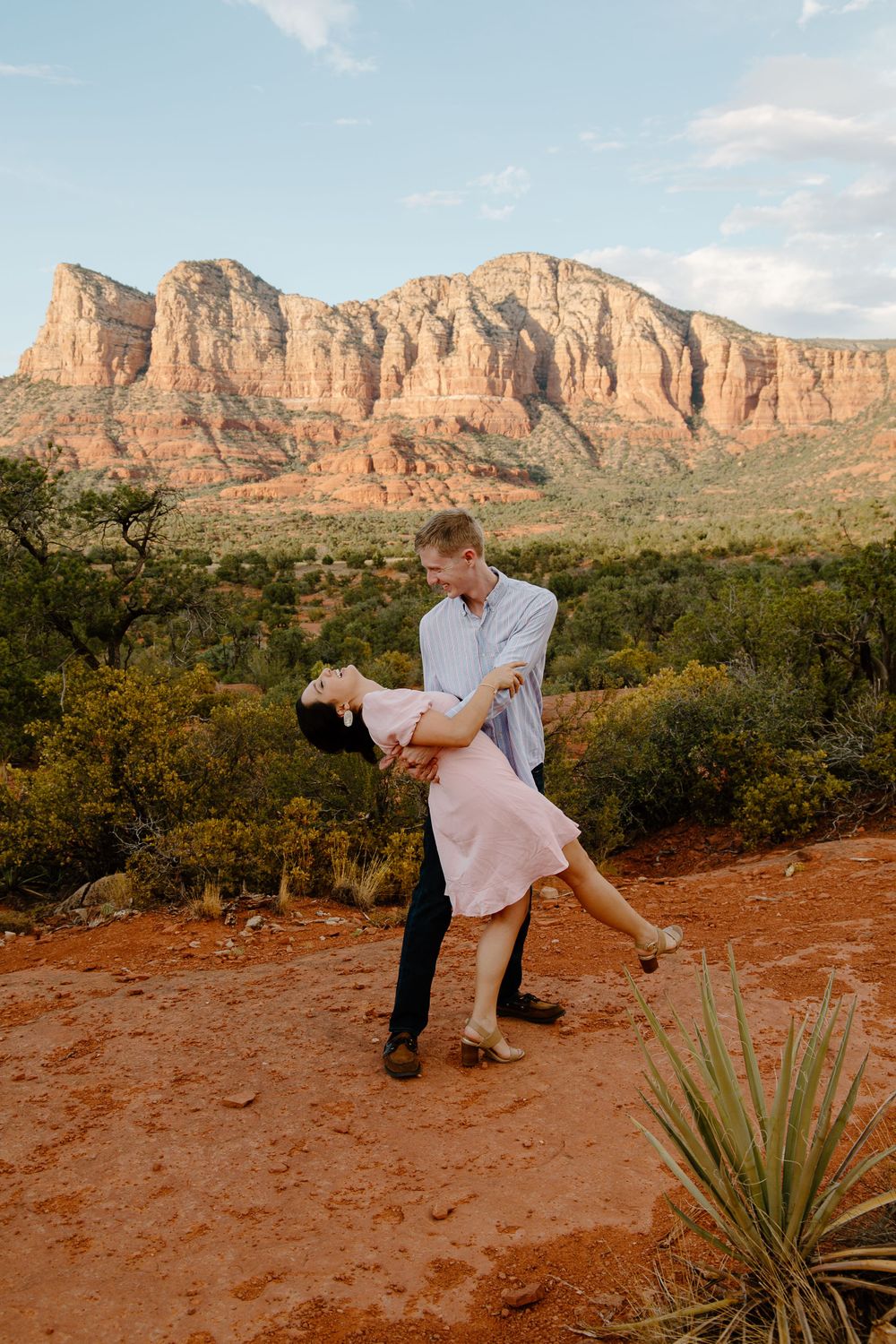 man dipping a woman back as she is laughing with a desert landscape in the background