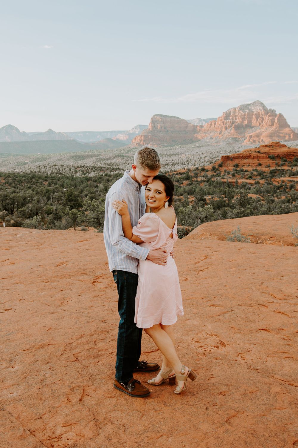 couple embracing as the woman is smiling and the man is looking down at her during their Arizona engagement session