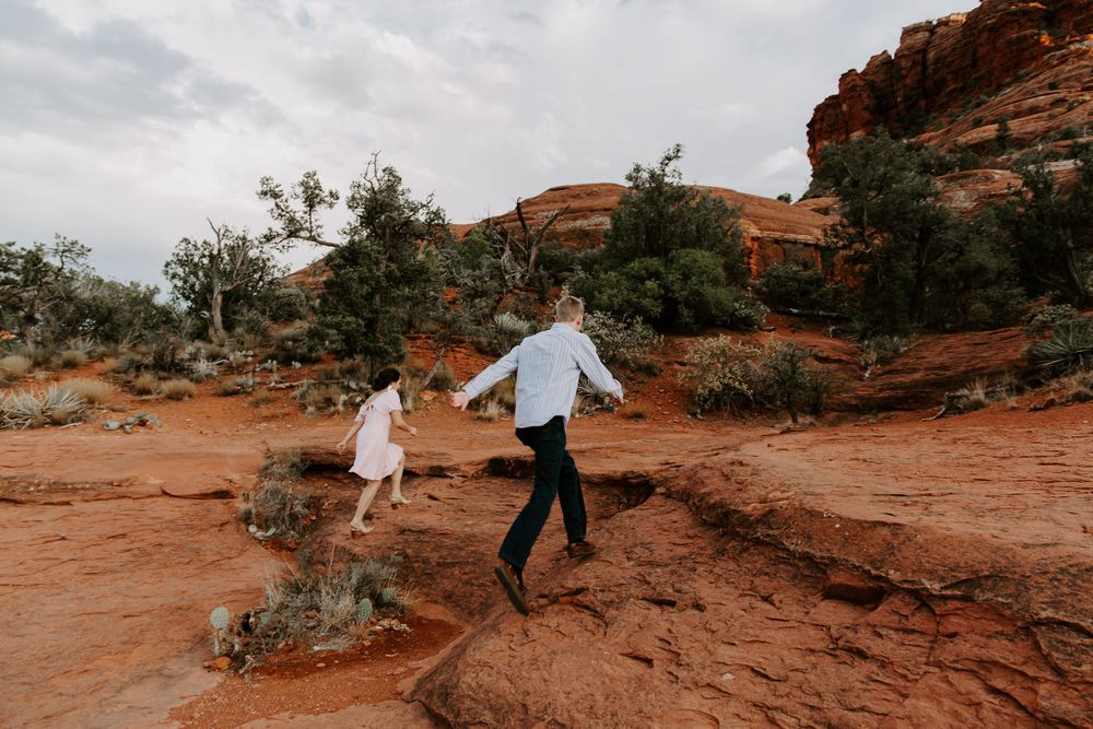 man and woman climbing up red rocks in Arizona during their Sedona photoshoot
