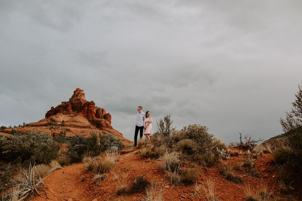 couple holding hands standing on top of red rocks in Sedona Arizona during their couples session