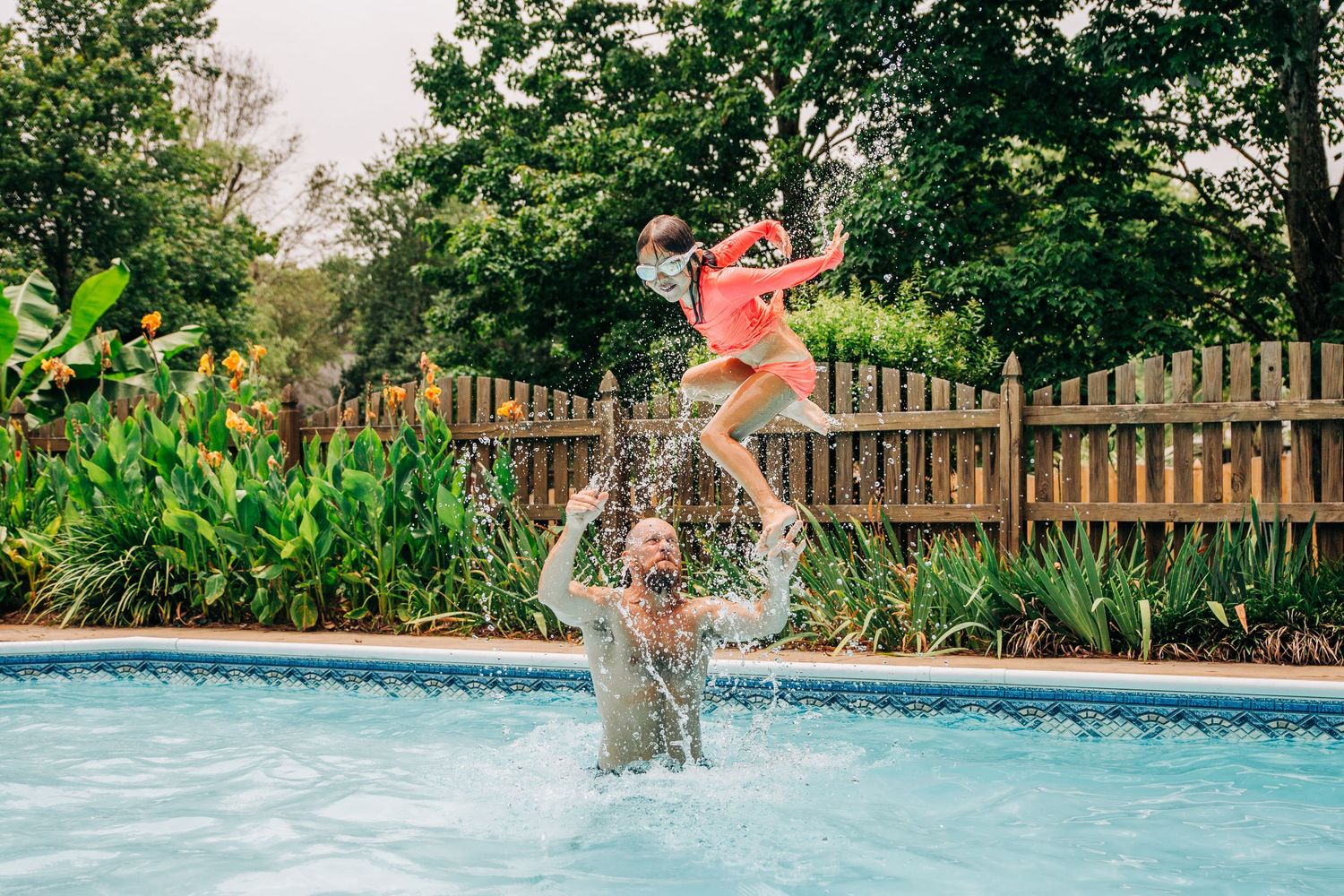 Dad throwing little girl in air in the pool