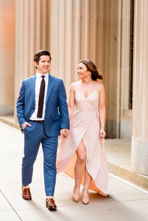 woman in blush pink dress holding hands with man in navy suit walking around Chicago Board of Trade
