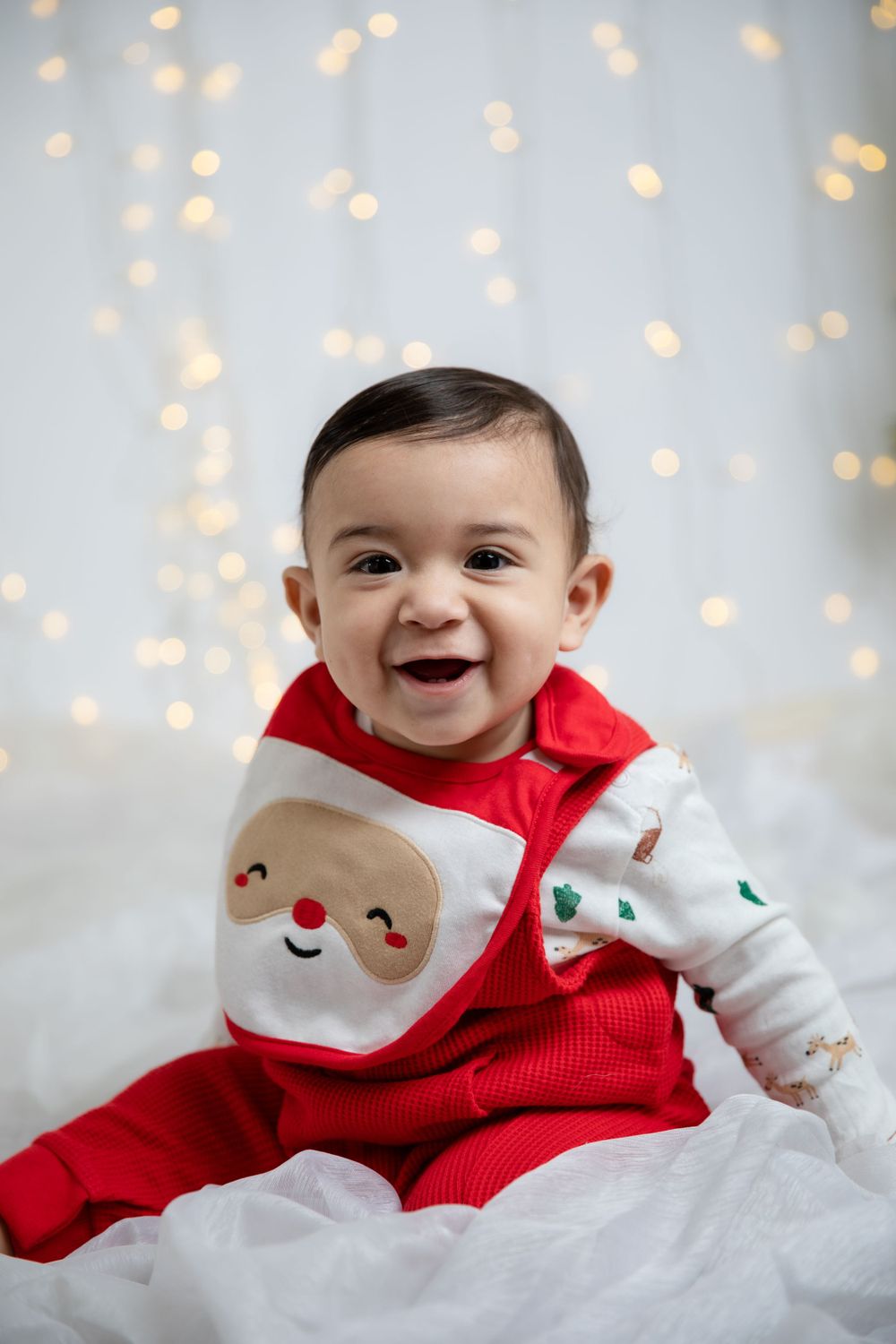 Holiday photo featuring festive Santa outfit against twinkle light background.