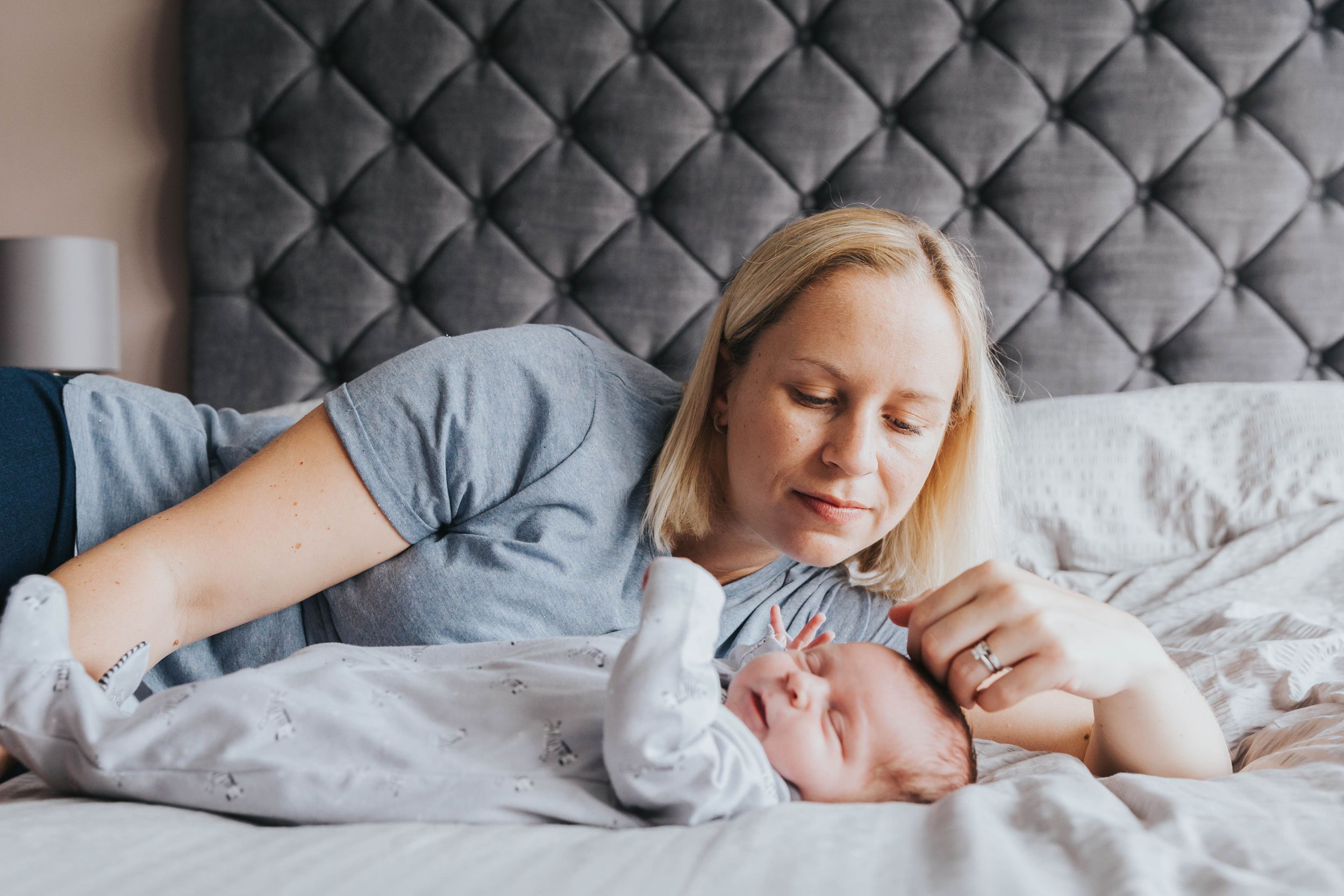 blonde woman laying on bed with new born son
