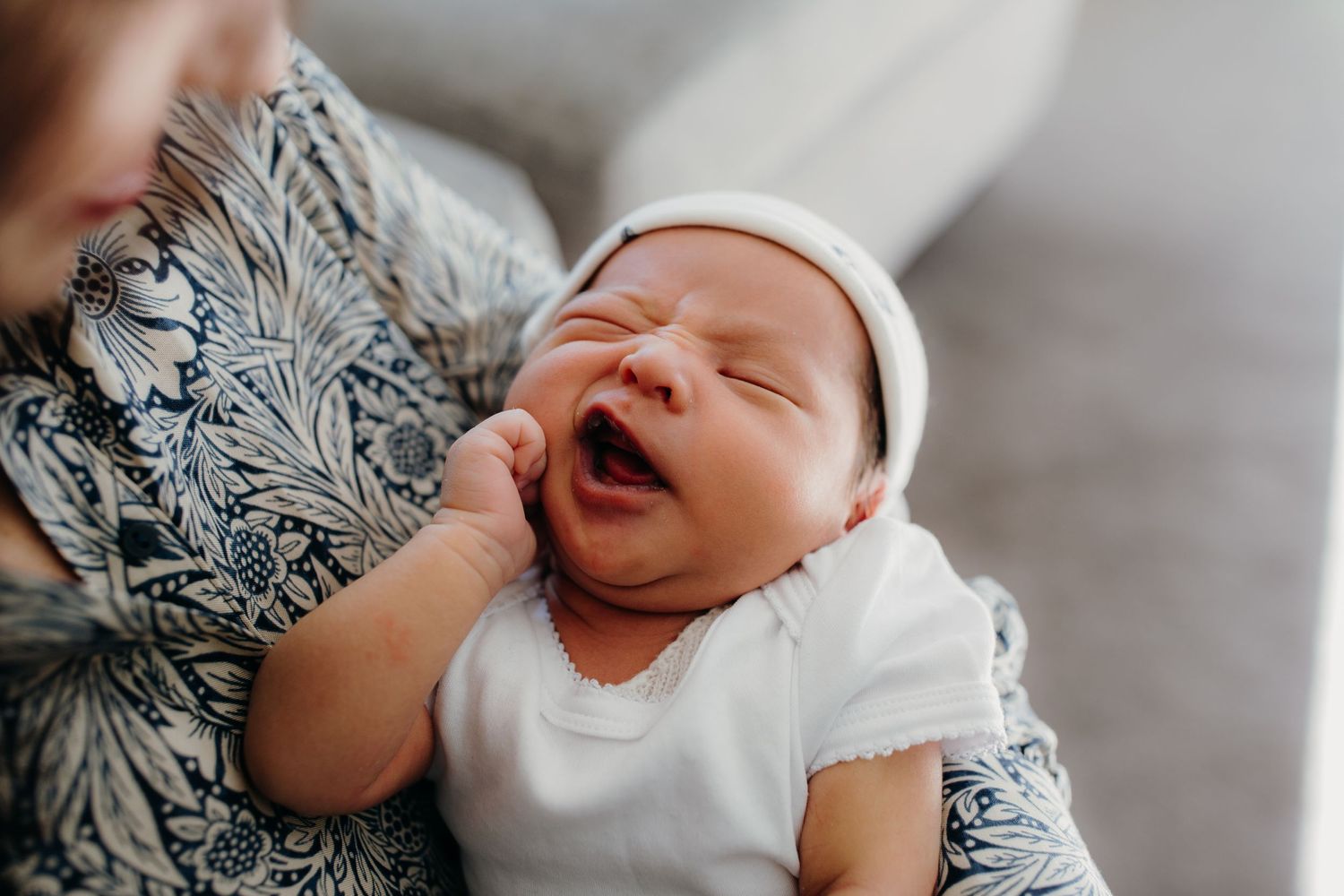 newborn baby yawning while being held by his mum