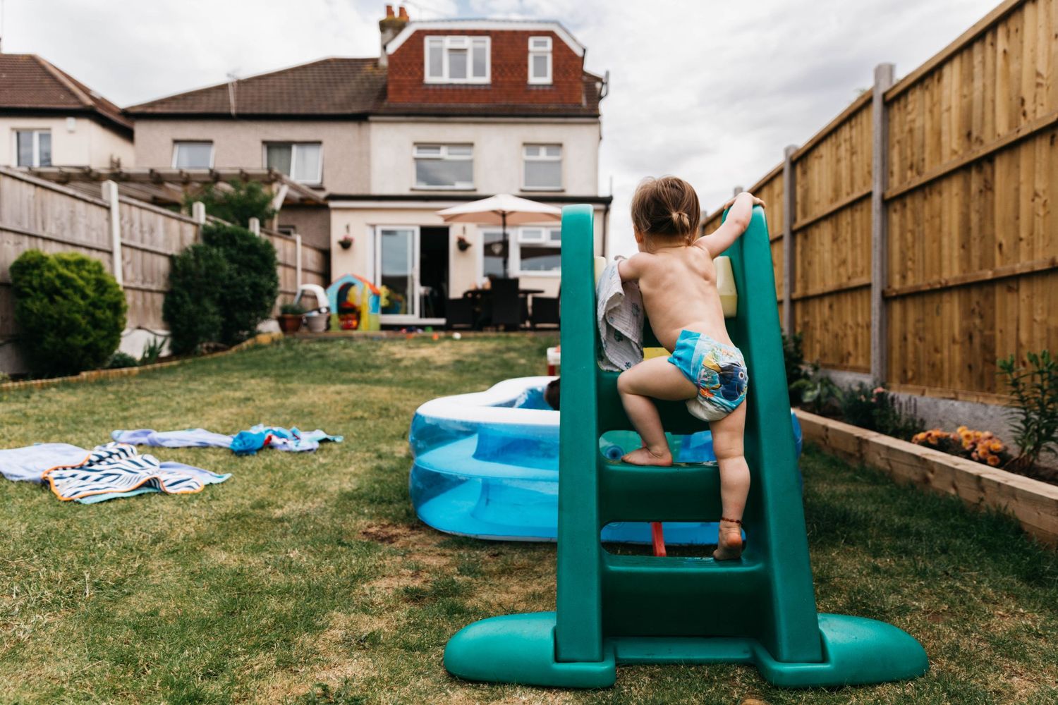 little girl climbing up steps on slide in garden