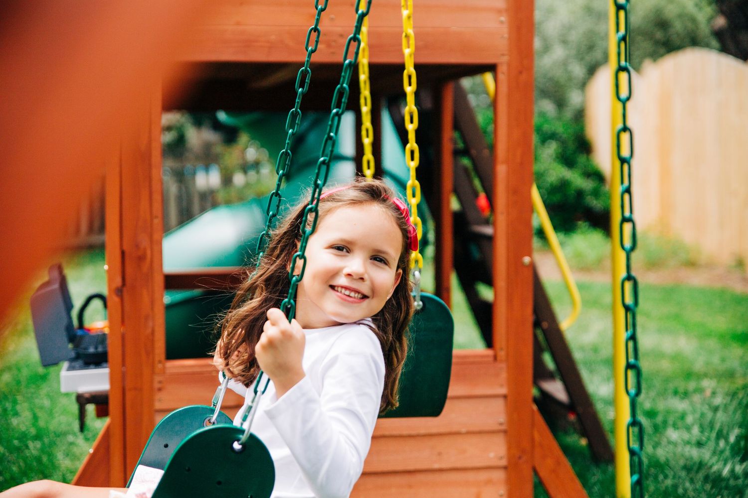 Young girl sitting on swing set during documentary family photography session in Charlotte, NC