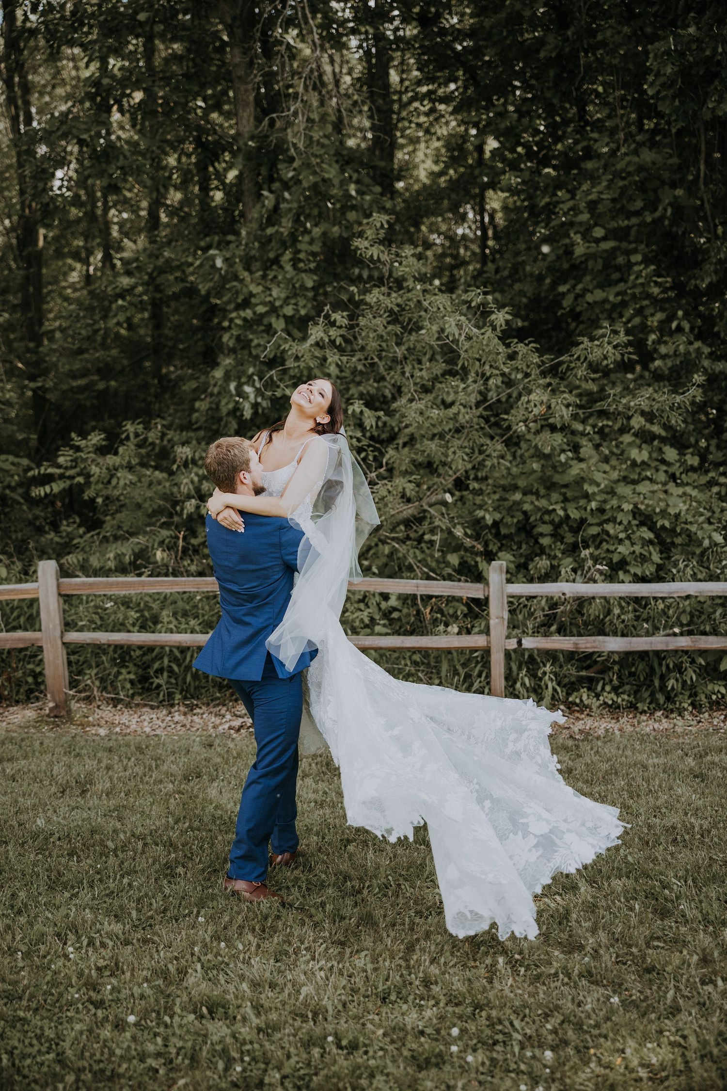 A rustic barn wedding venue with wooden walls, green shutters and a couple sharing an intimate moment in front of the doors.