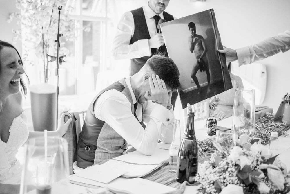 Black and white photo of guests enjoying a celebratory moment at a wedding reception with table decorations and flowers.