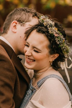 A joyful wedding couple sharing intimate moments together with dried floral crown details and warm autumn tones.