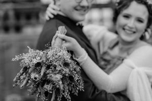 Black and white close-up of joyful couple on their wedding day holding a delicate bouquet of baby's breath flowers.