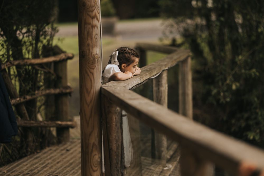A young flower girl rests on wooden railing with blurred green foliage in background at Grand Lodge Oaklands - taken by Grimsby photographer