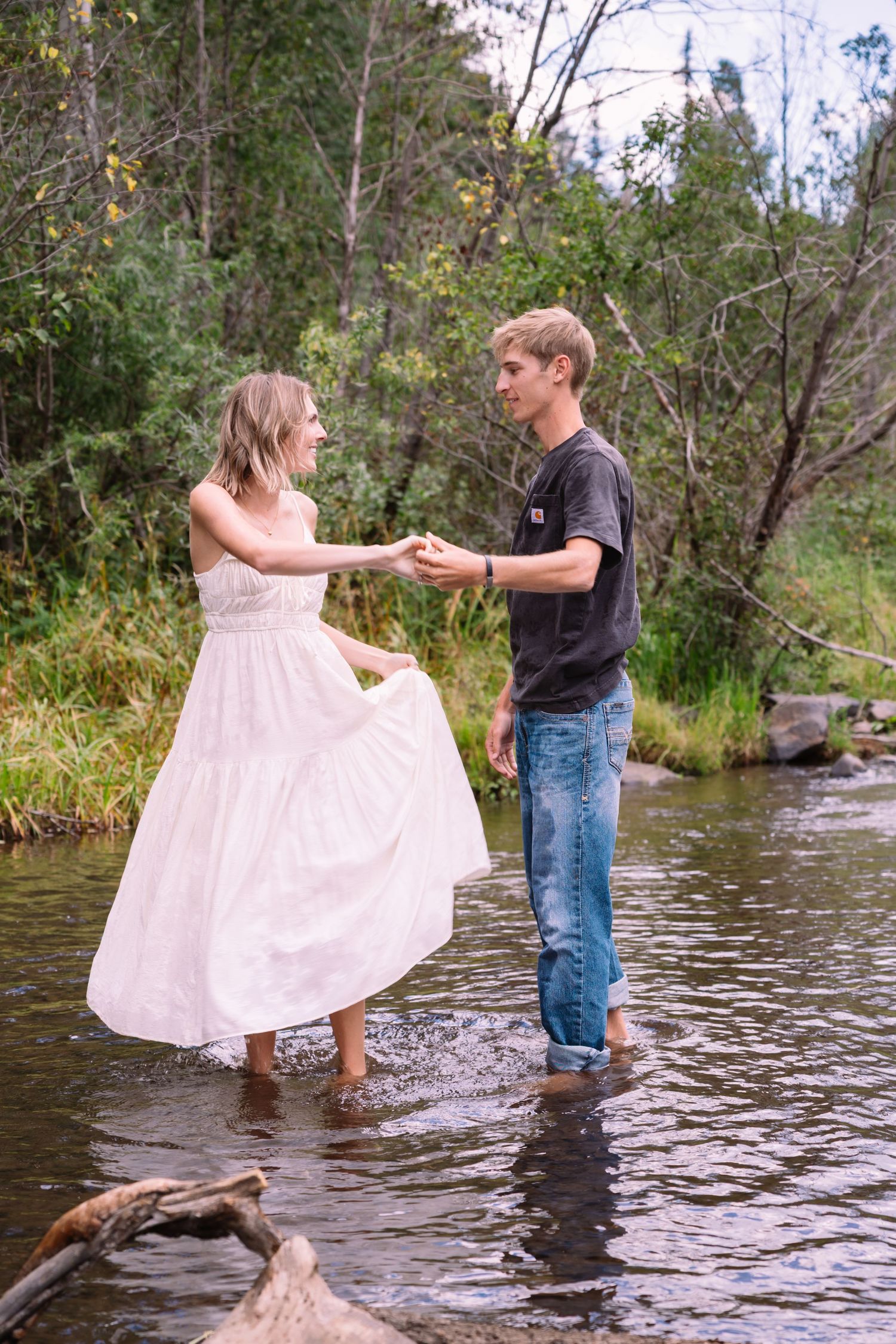 A couple playfully dances in a flowing stream, with the woman twirling as they wade through shallow waters. Knoxville Photographer