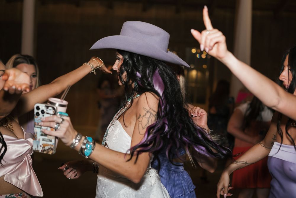 People dancing and celebrating at a reception with someone wearing a cowboy hat.