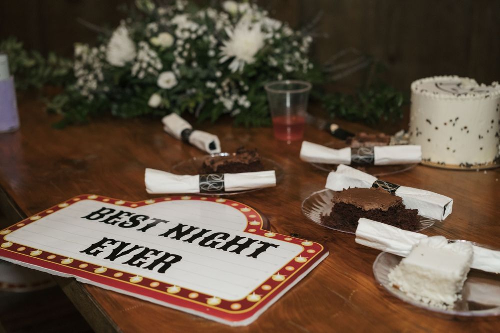 Movie night decorative sign and scattered popcorn containers on rustic wooden table with floral arrangement.